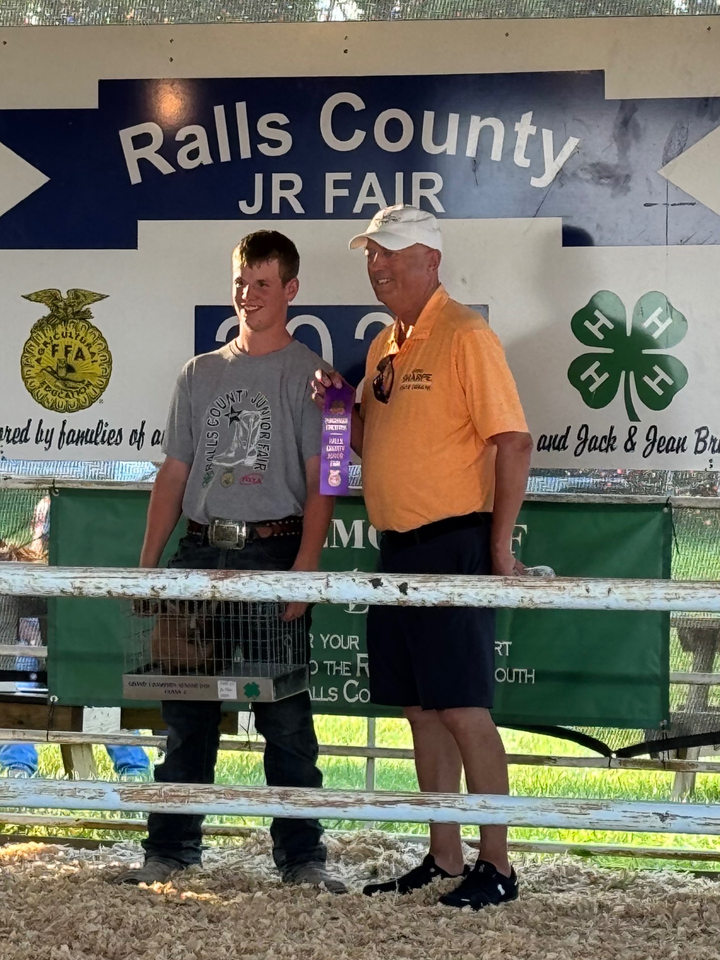 Greg Sharpe presenting a purple ribbon to a young FFA exhibitor at the Ralls County Junior Fair
