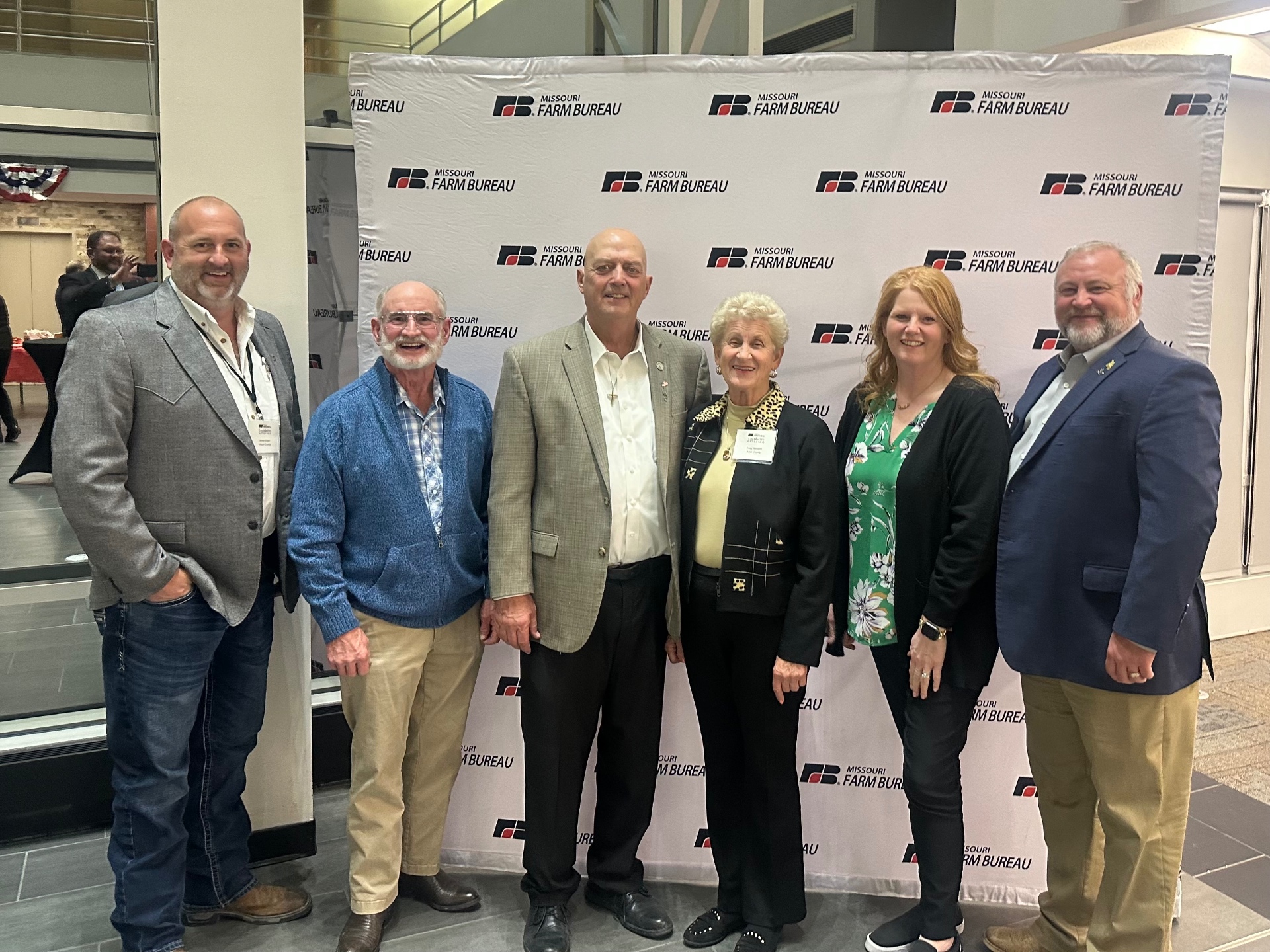 Greg Sharpe with Missouri Farm Bureau members in front of the Missouri Farm Bureau backdrop